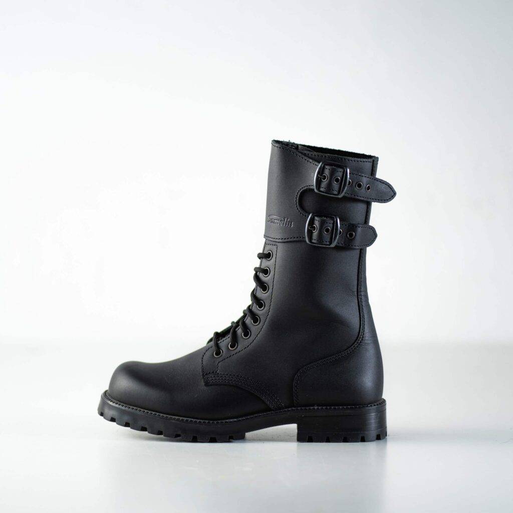 Sorte læderstøvler med spænder og snørebånd på en lys baggrund.