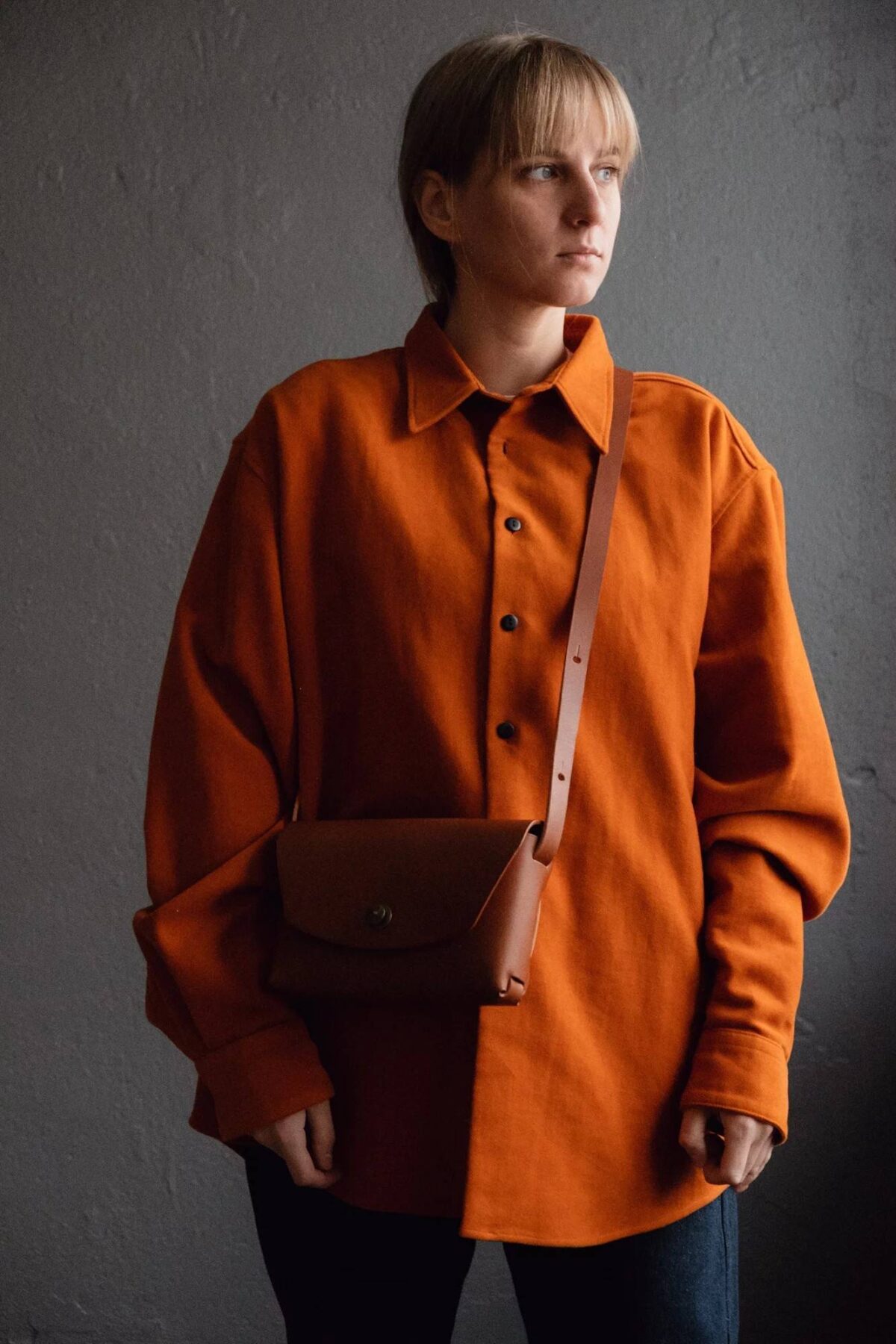 Moderne læder clutch taske, båret over en stilfuld orange skjorte.